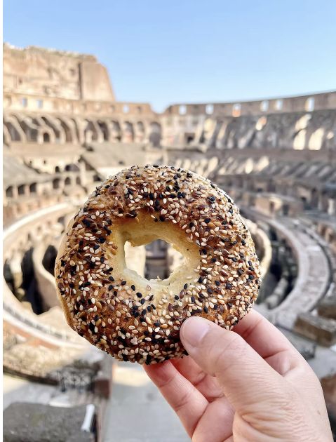 An everything bagel held up inside the Colosseum